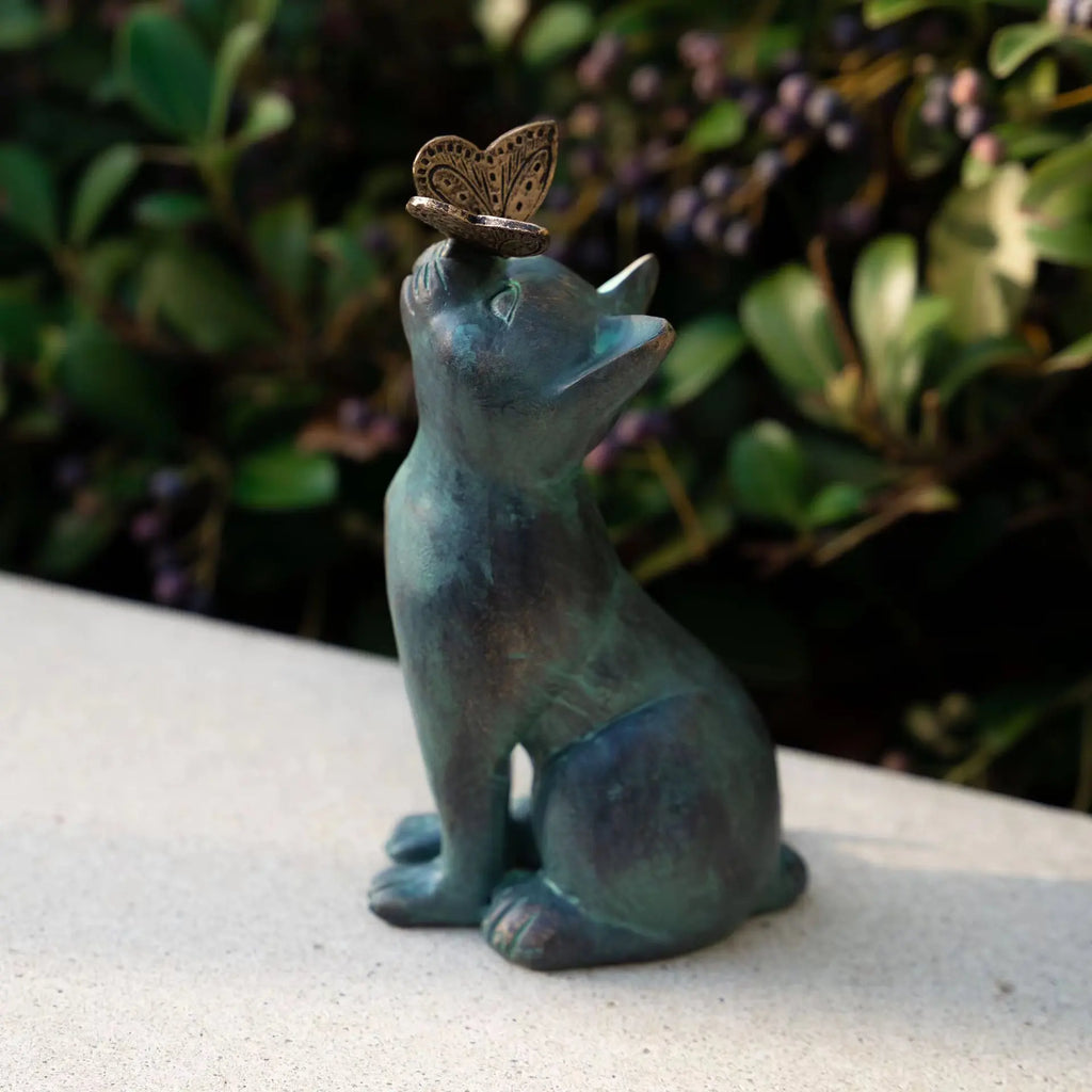 Cat and butterfly resin statue displayed on a patio ledge