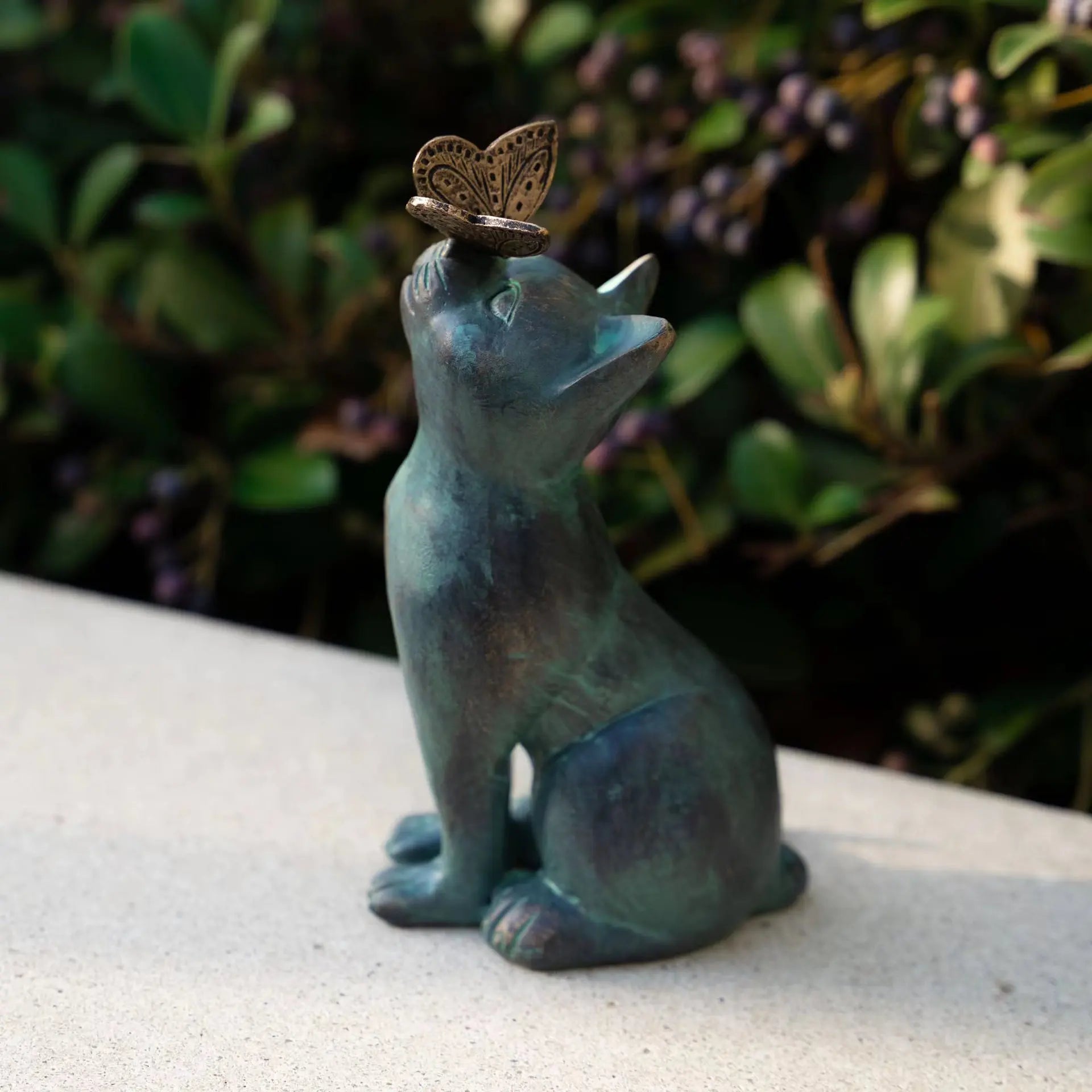 Cat and butterfly resin statue displayed on a patio ledge