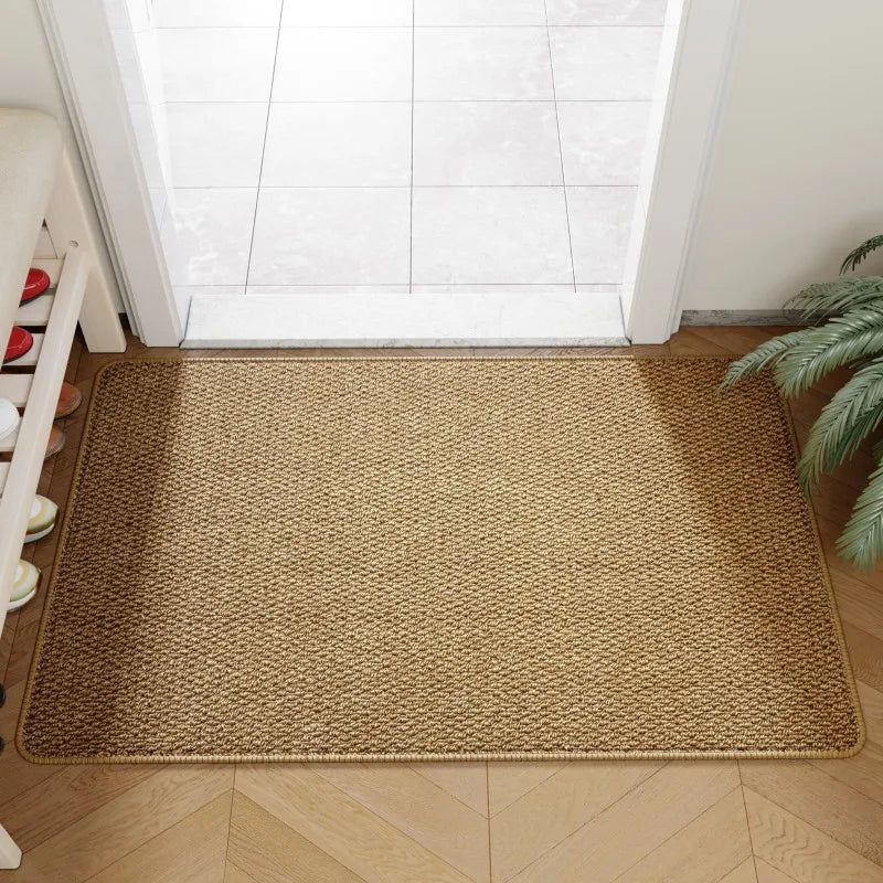 Faux jute doormat in brown placed at an indoor entryway with tiled threshold and a houseplant nearby