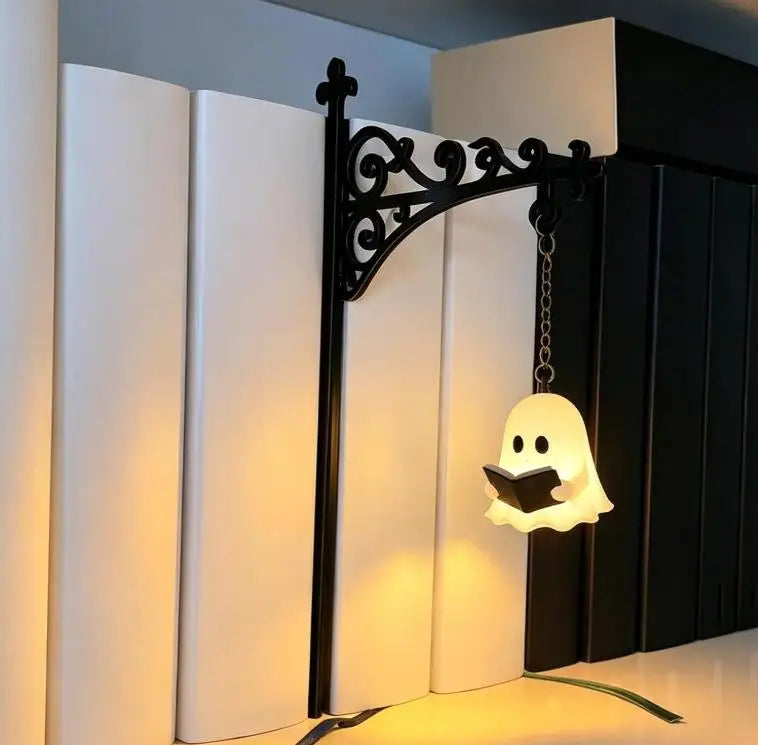 Warm LED ghost bookshelf lamp lit on a white shelf with books