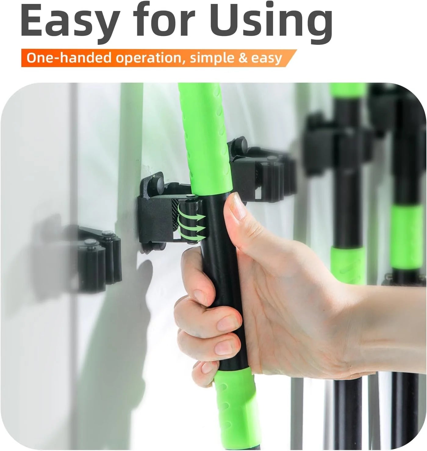 Hand placing broom handle into a black wall-mounted broom holder on a wall