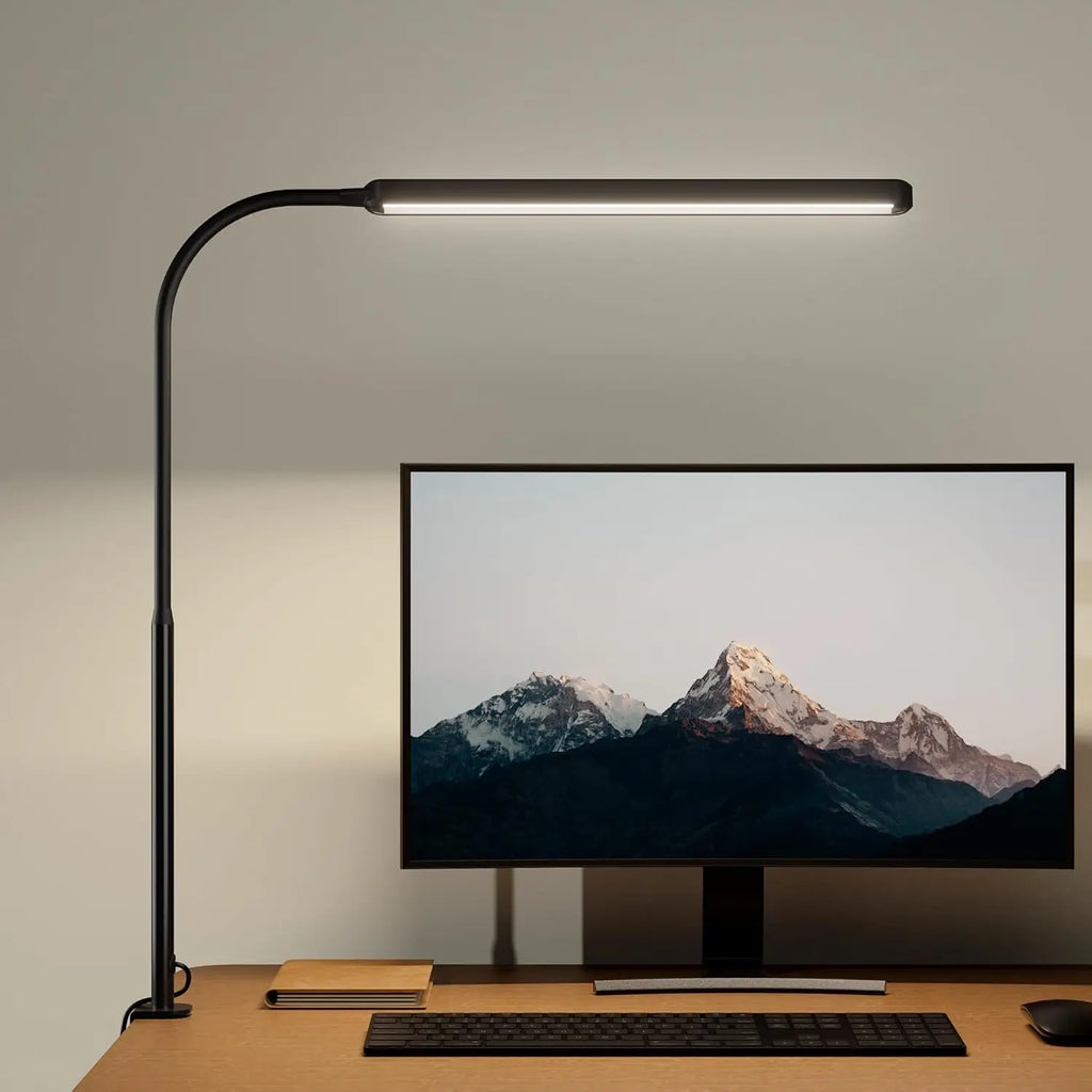 Black clamp-on LED desk lamp with a long gooseneck positioned above a computer monitor