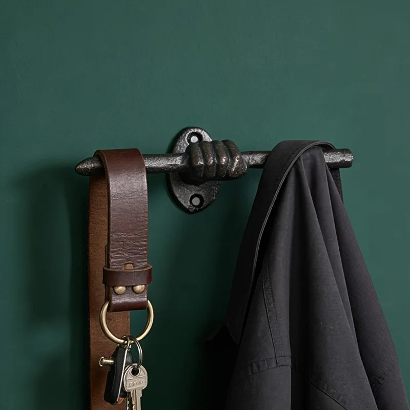 Hand shaped cast iron wall hook on green wall, hanging coat and keychain