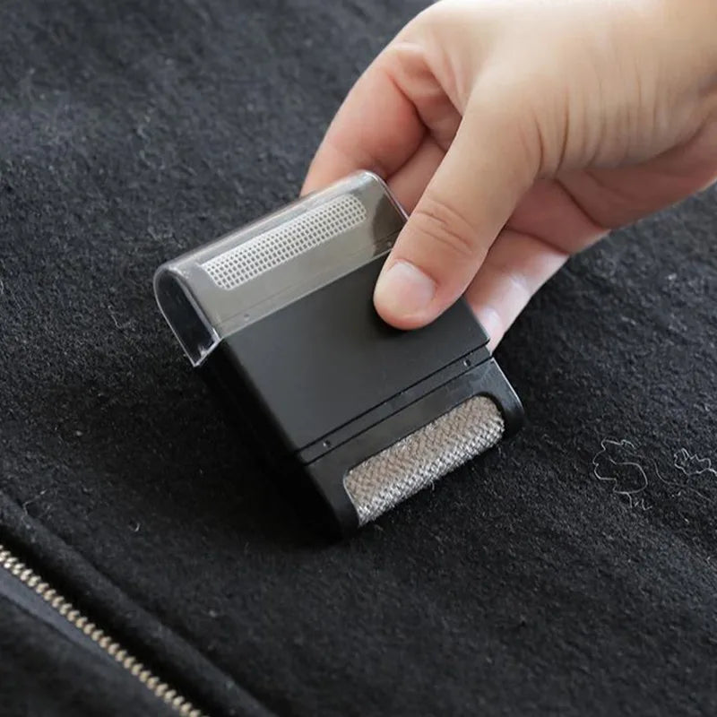 Mini lint brush in black lifting lint from a black jacket
