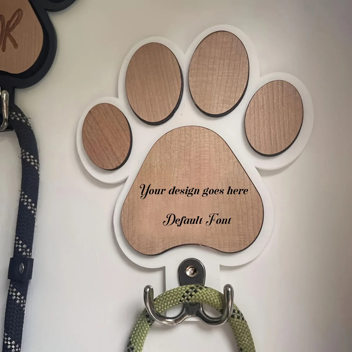 Close-up of a white paw print wall hook with wood center, holding a dog leash