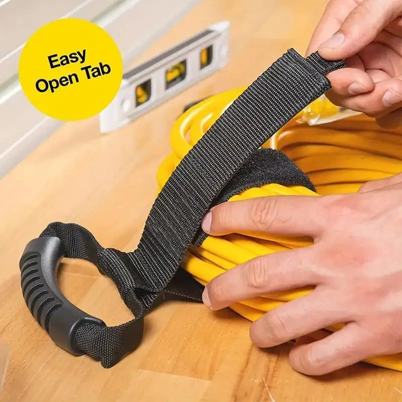 Hand using tab to open and fasten hook-and-loop strap over a coiled yellow cord on a workbench