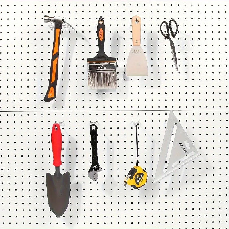 variety of tools including hammer, paintbrush, wrench, and tape measure organized on a white pegboard using metal hooks