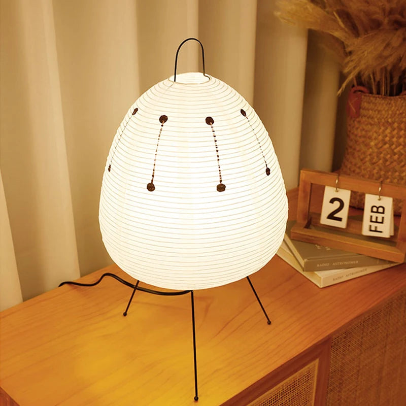 Handmade rice paper table lamp unlit on a wooden table with books and natural decor in a cozy interior