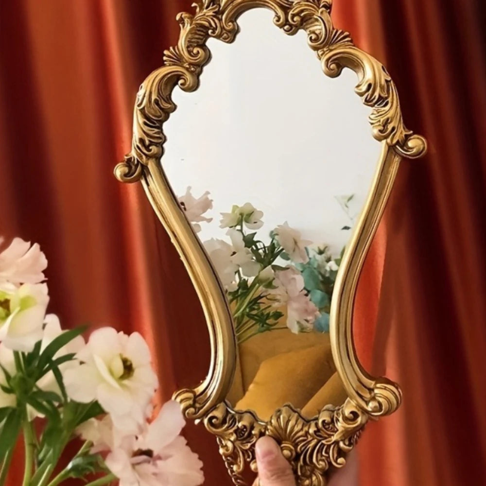 Hand holding a vertical gold carved frame mirror with flowers reflected