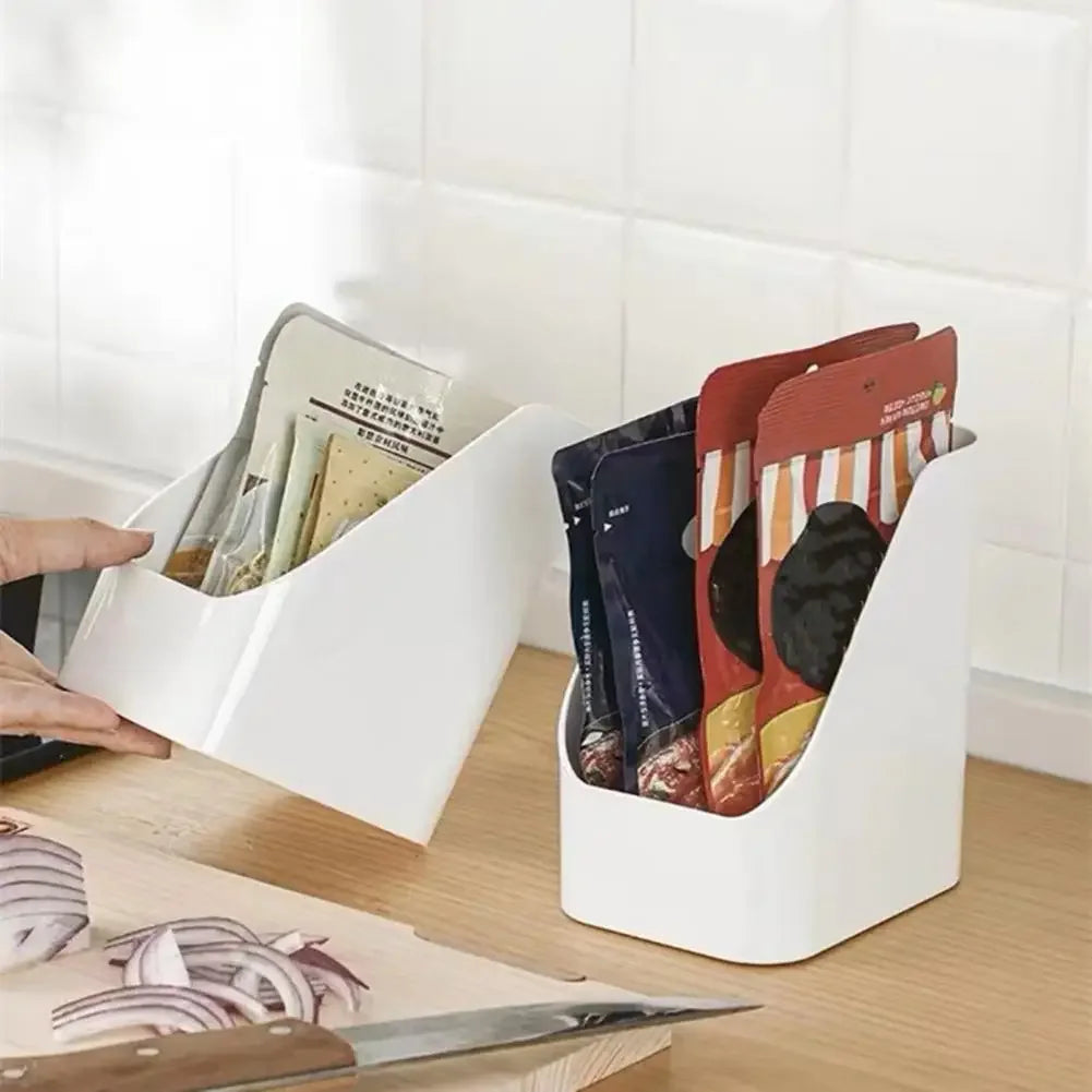 Two white organizer bins holding snack packages on a kitchen counter
