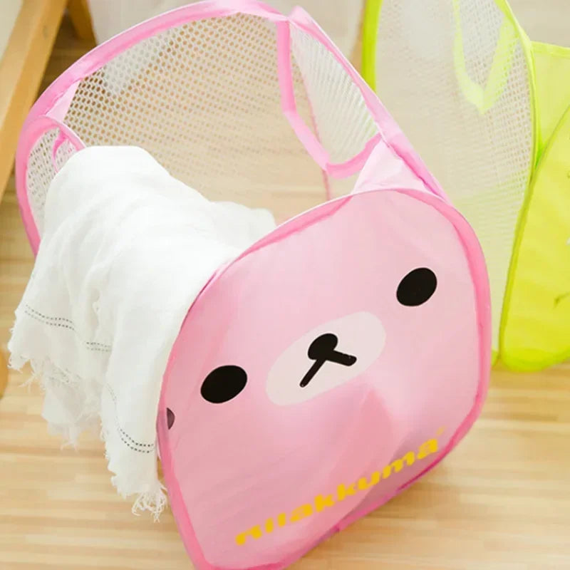 Pink bear cartoon mesh pop-up hamper holding a white towel on a wooden floor