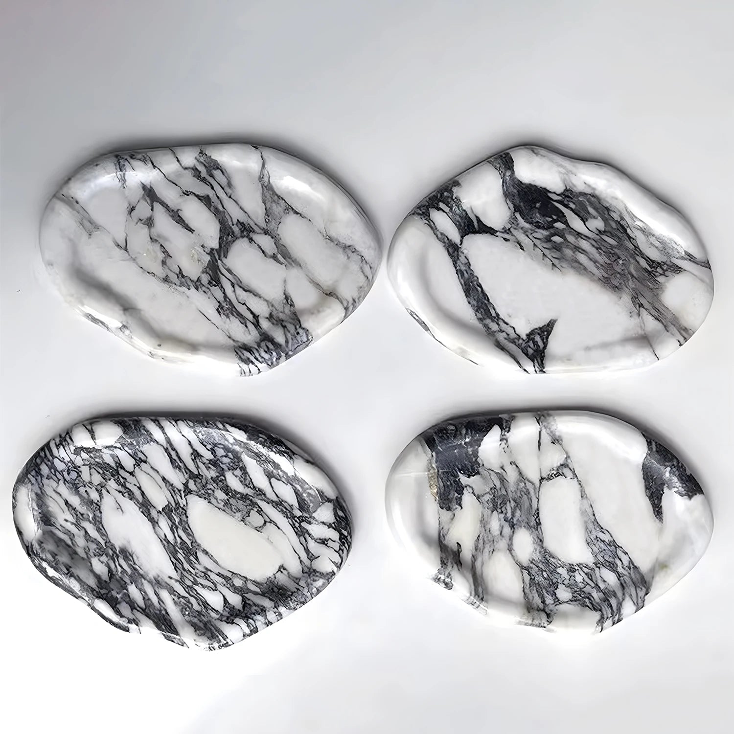 Four marble-pattern irregular ceramic trays displayed on a white background