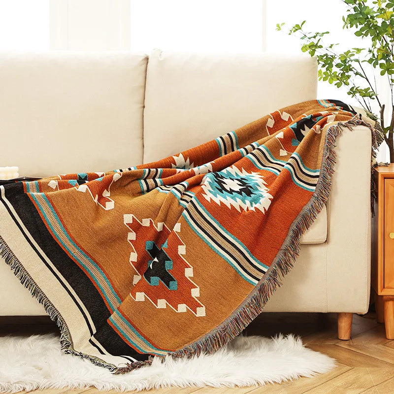 Orange and teal geometric woven throw blanket draped over a cream sofa in a cozy living room