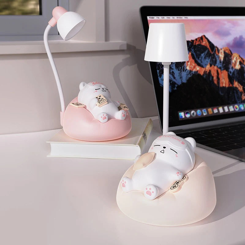 Two animal LED night lights, pink and white, placed on a book and desk near a laptop