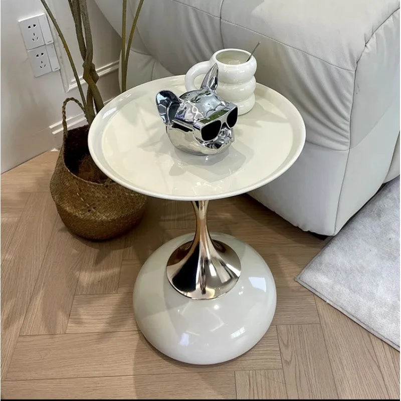 Modern white and gold metal side table next to a couch, styled with a mug and decor