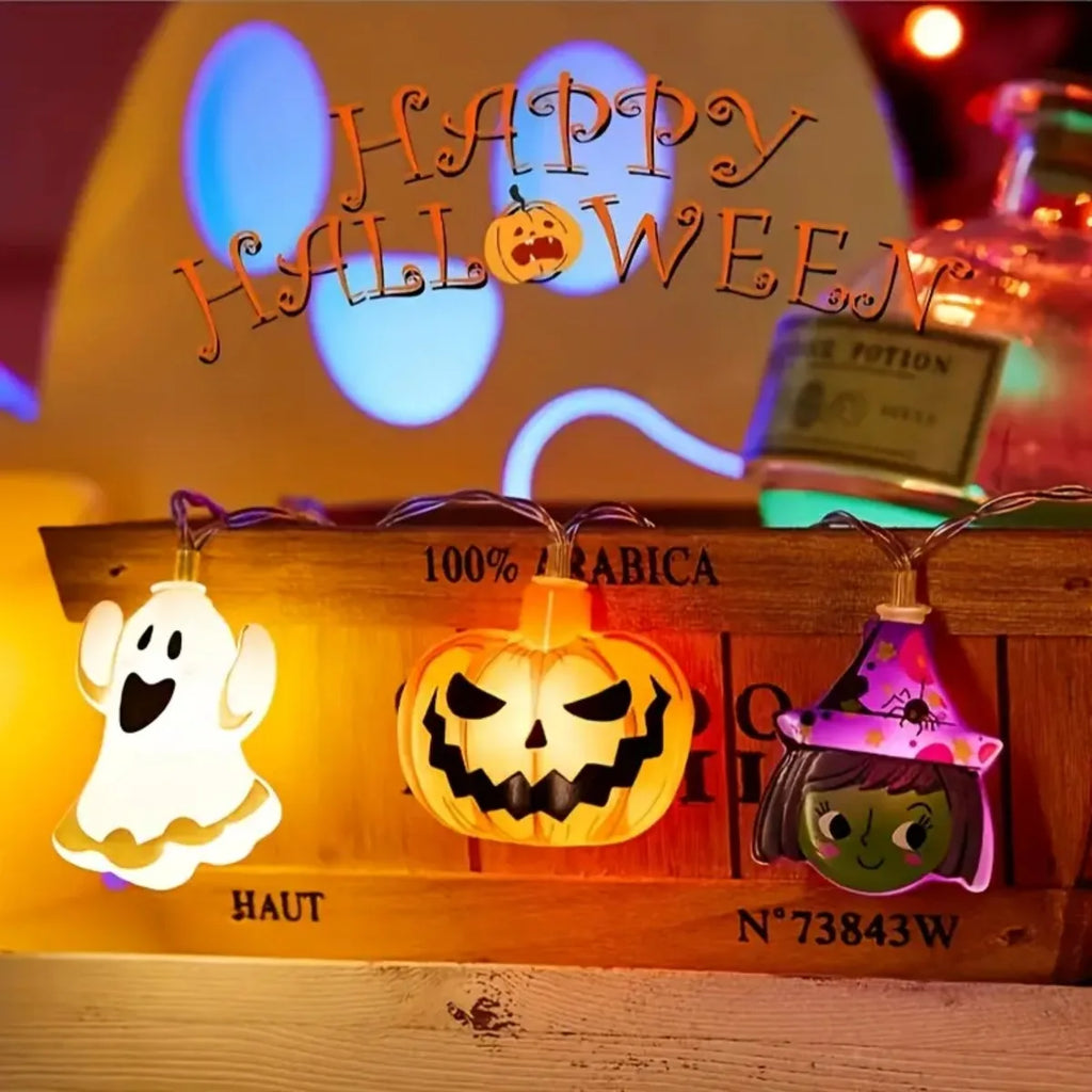 Close-up of ghost, pumpkin, and witch Halloween LED string lights glowing in front of a wooden crate with Halloween decor