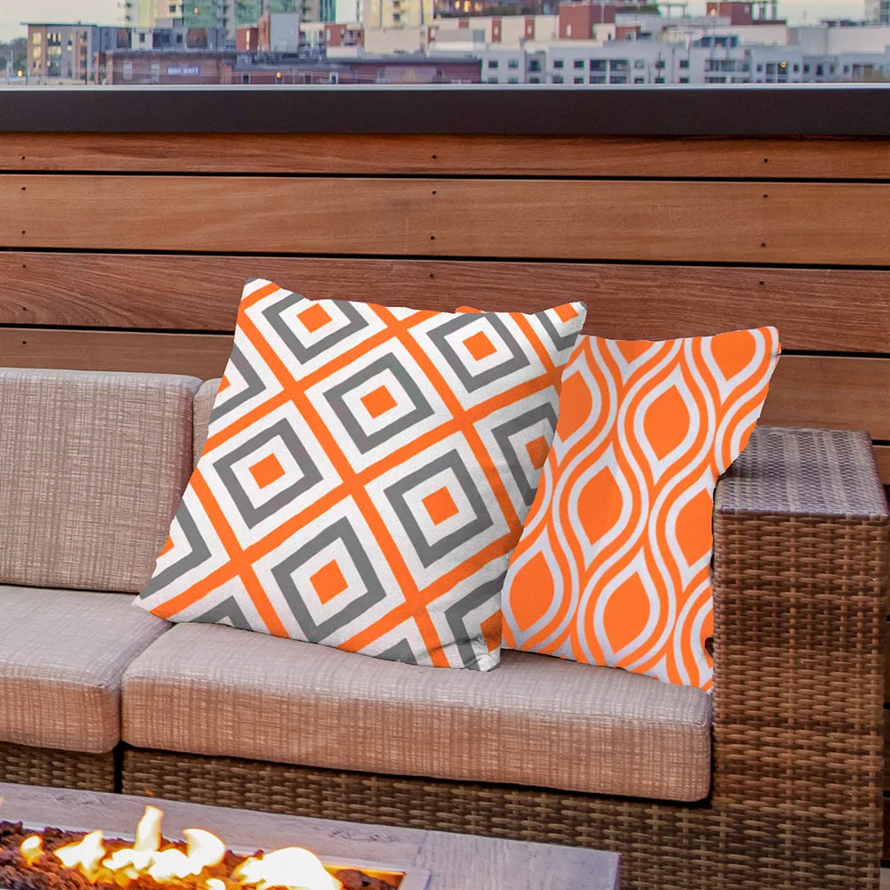 Close-up of orange geometric and diamond patterned outdoor cushion covers on woven patio furniture