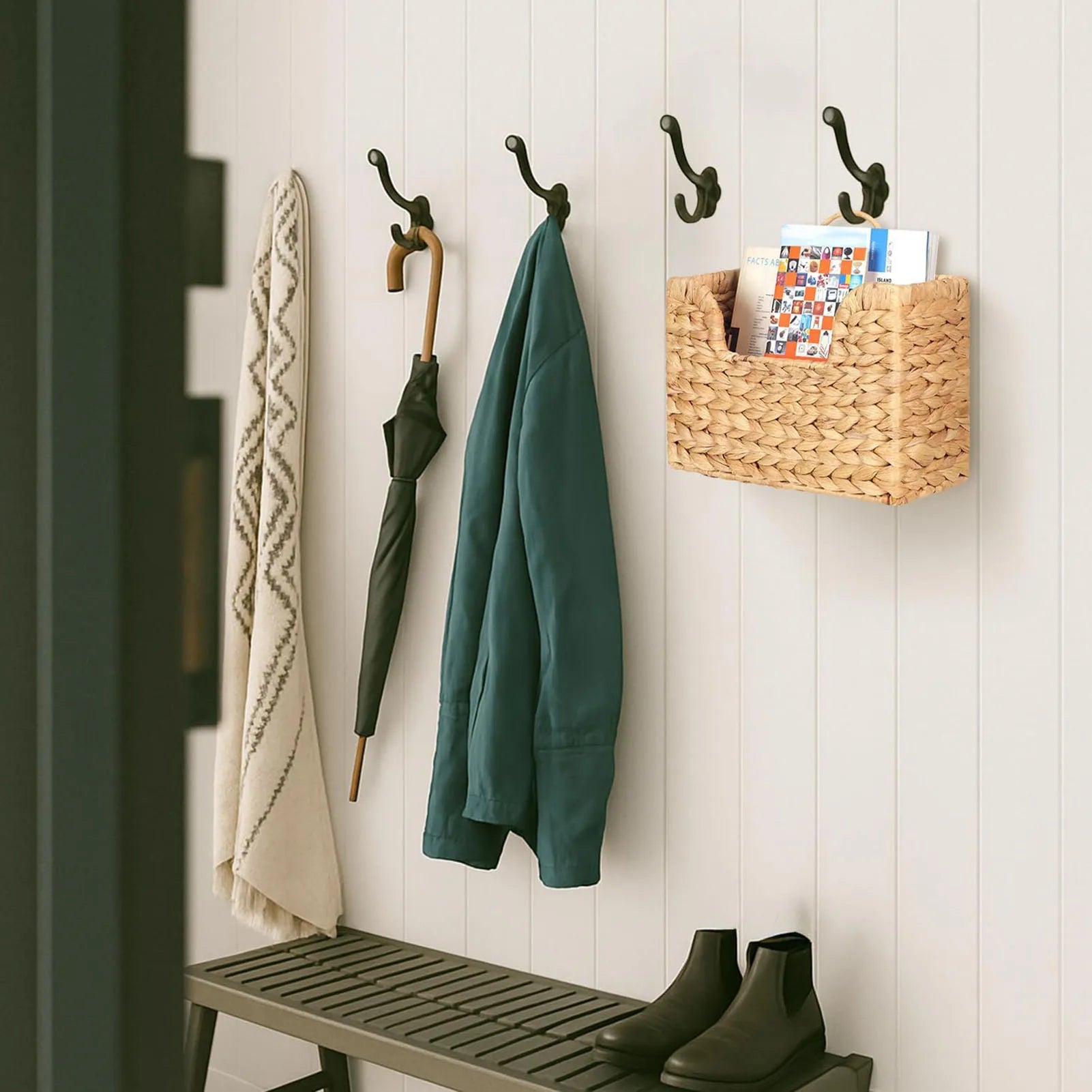 Woven wall basket used as a mail and paper organizer in an entryway, hanging by coats and umbrella