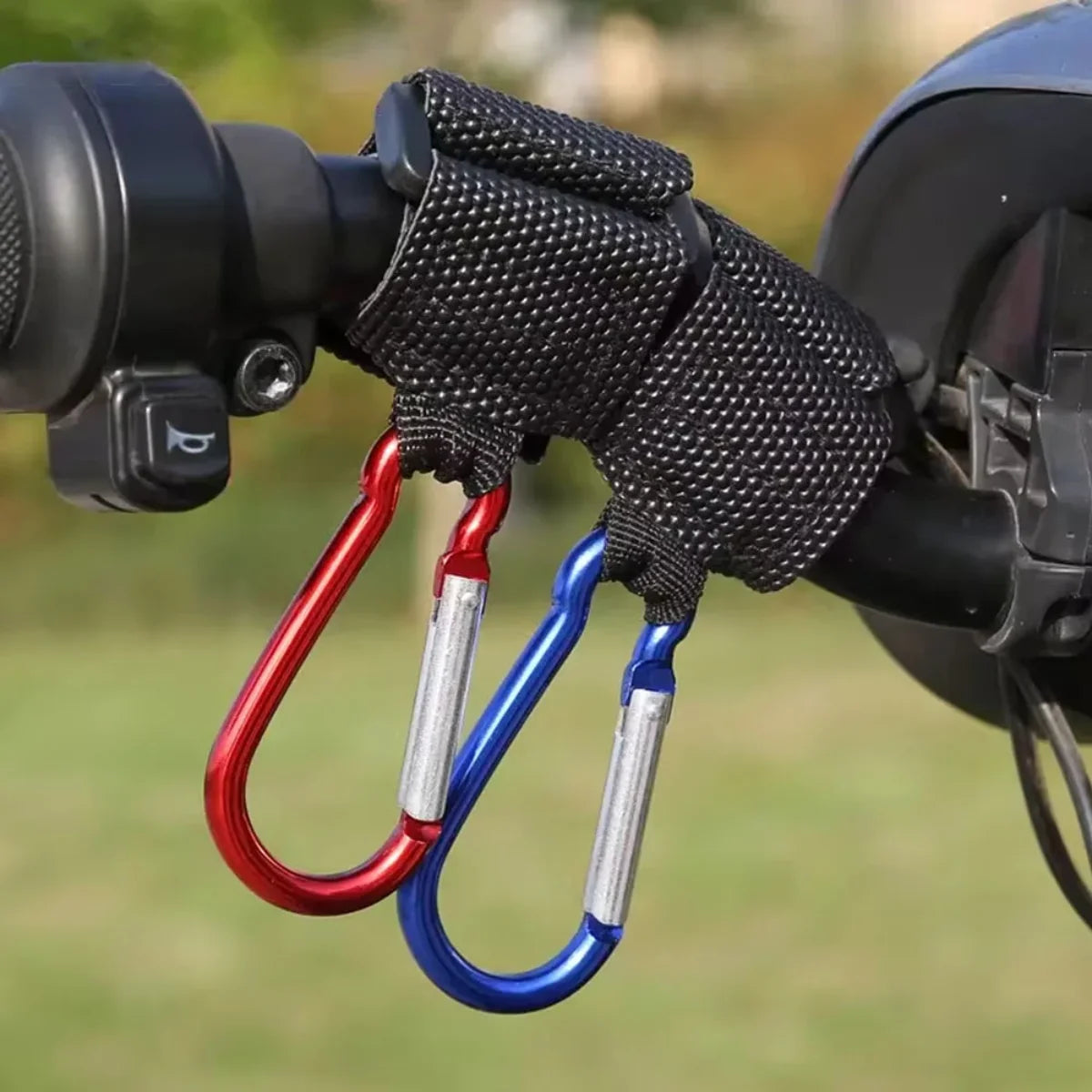 Universal handlebar locking hooks with black straps holding red and blue carabiners attached to a bike handlebar outdoors