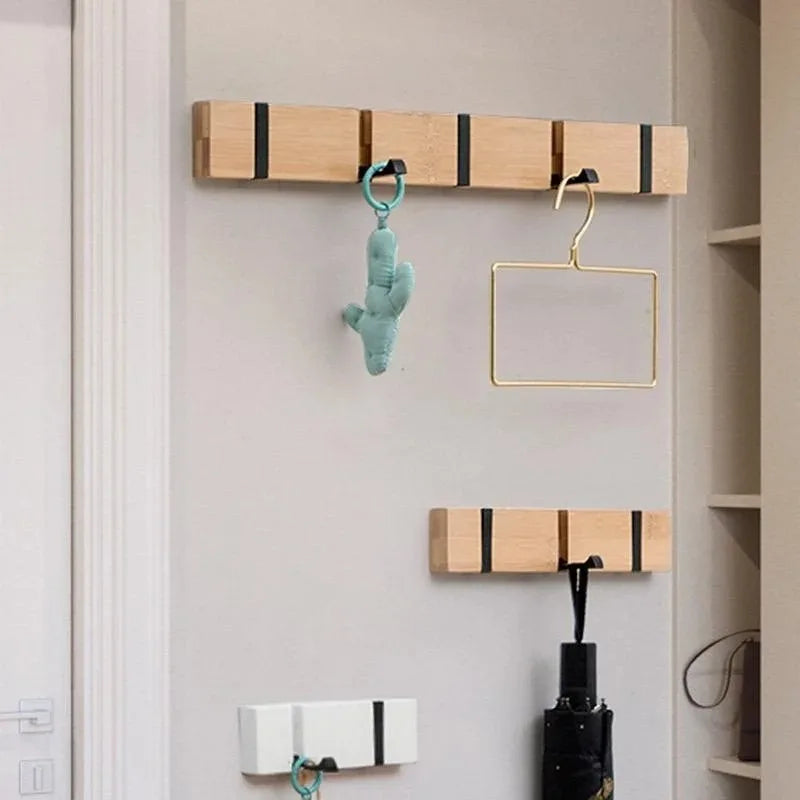 Mix of white and natural wood foldable wall hook racks installed on a wall, each with different items hanging such as an umbrella and a toy