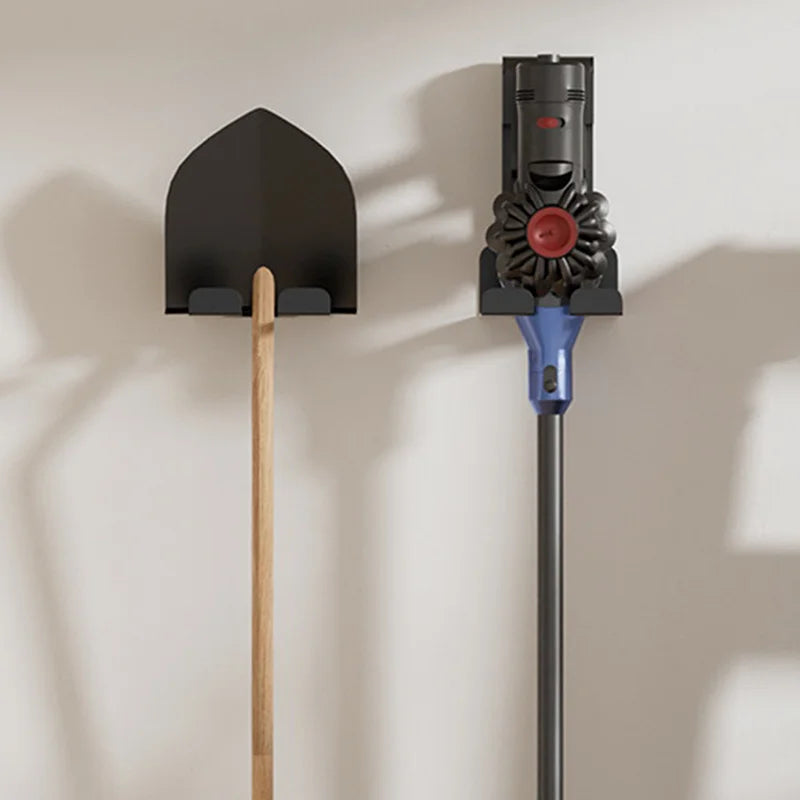 Black tool holder mounted on a wall holding a shovel and a cordless vacuum