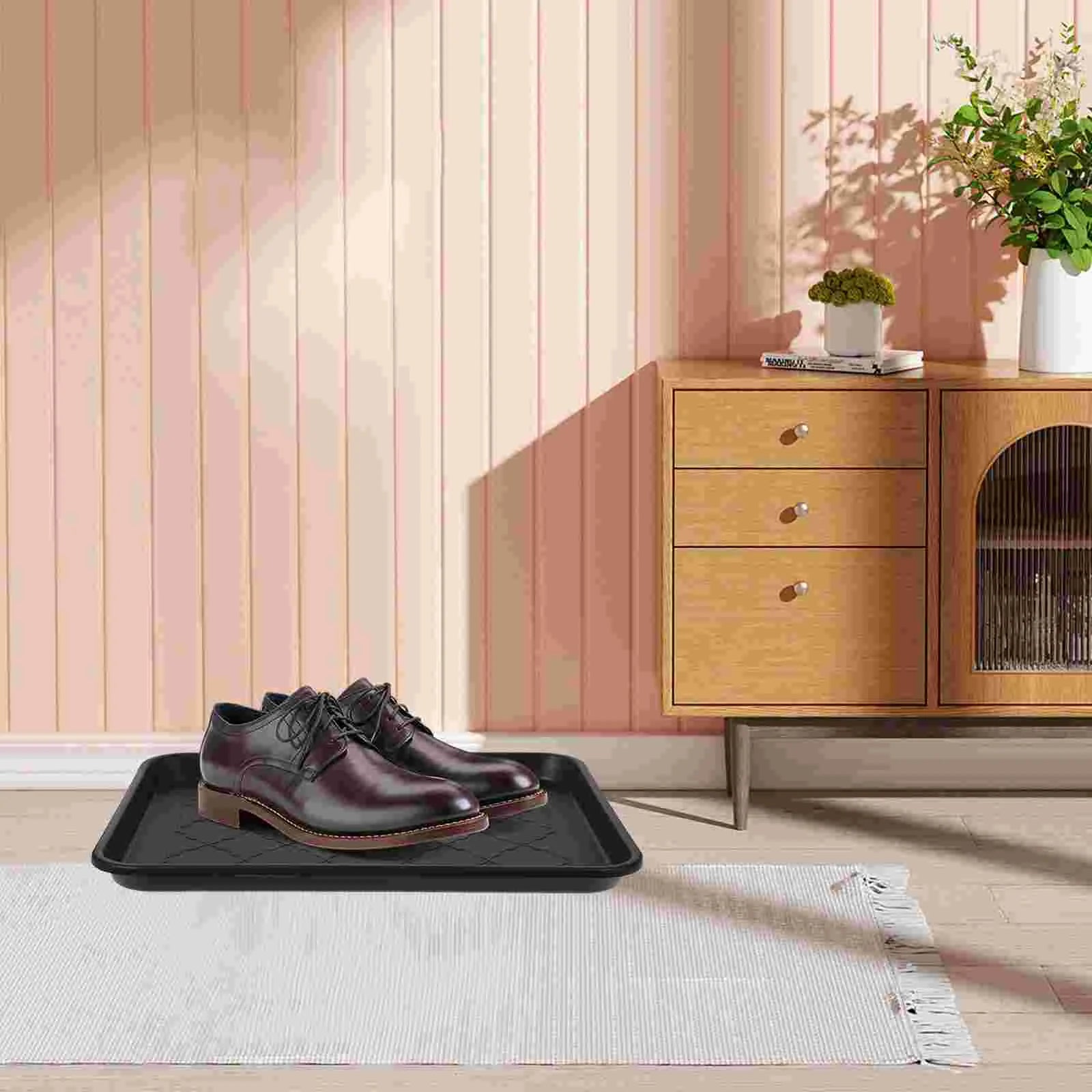 black shoe tray holding a pair of dress shoes on an entryway rug