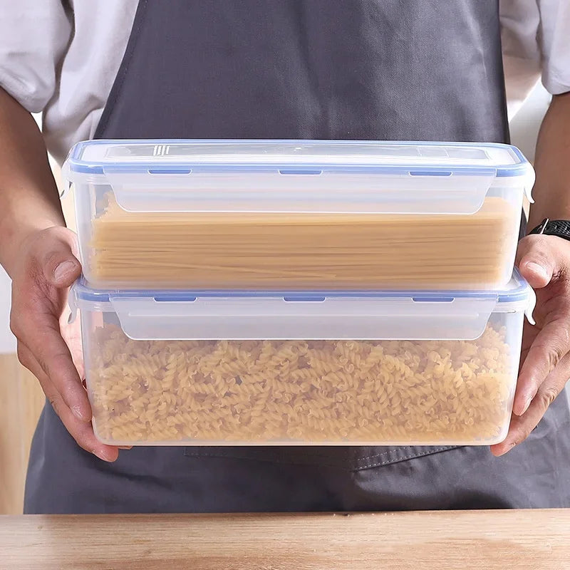 hands holding two stacked clear bread boxes, one filled with spaghetti and one with rotini pasta