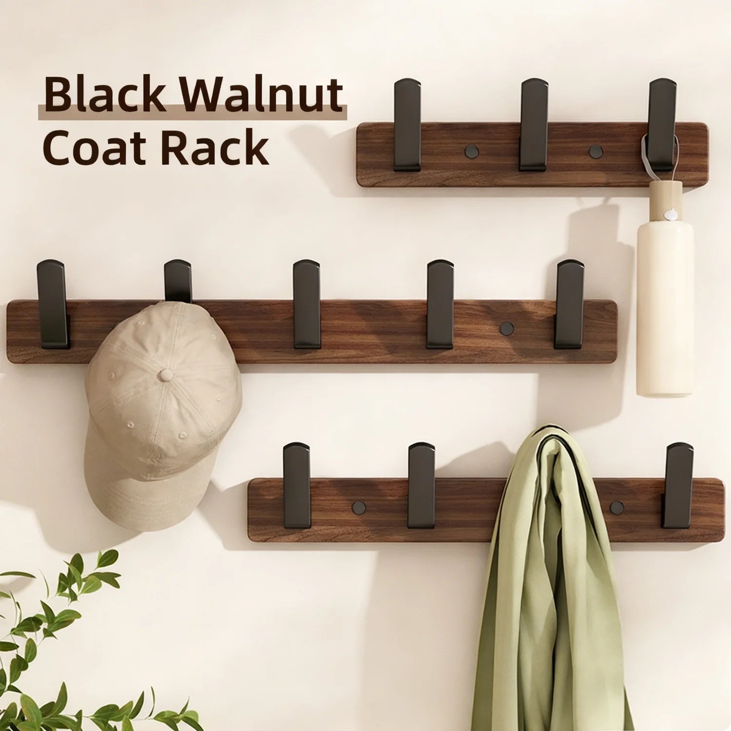 Set of three wall-mounted wood and metal coat racks labeled Black Walnut Coat Rack, one holding a hat and scarf in a light-filled entryway