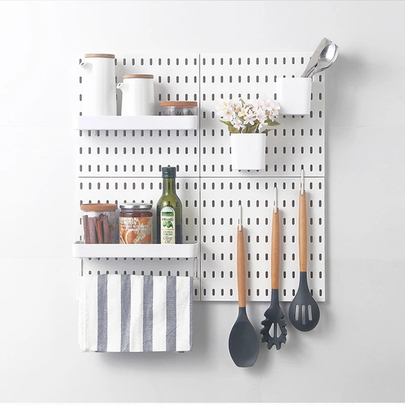 White pegboard wall with shelves, towel bar, jars, and small bins holding kitchen or pantry items