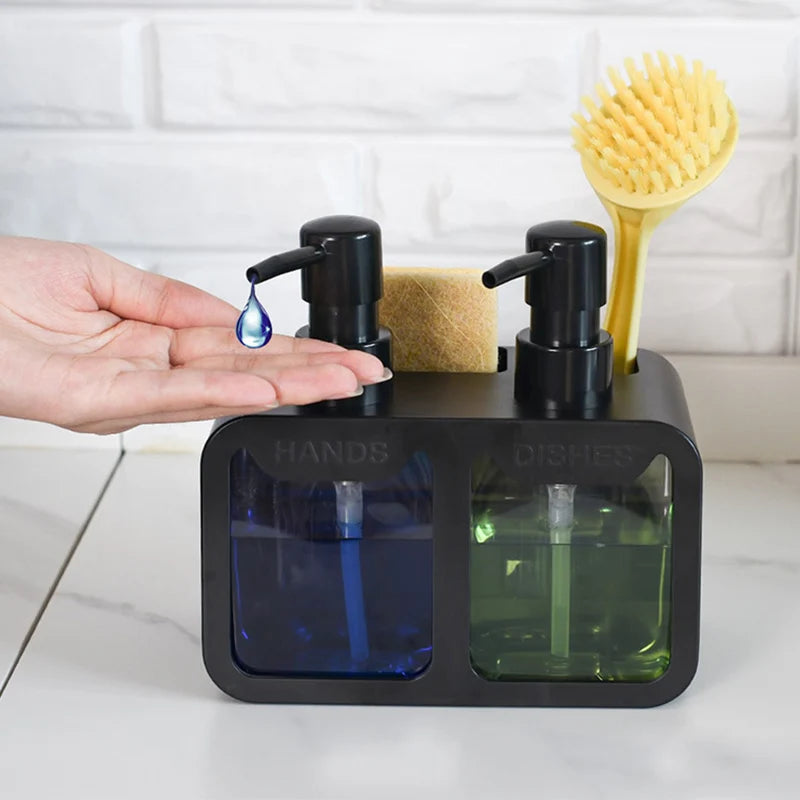 Black dual kitchen soap dispenser with labeled pumps for hand and dish soap, shown in use with a hand receiving soap, a sponge, and a dish brush stored on top