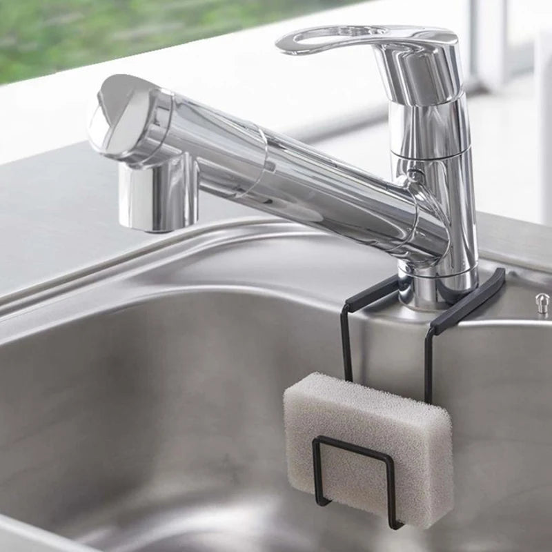 Black metal faucet sponge holder on a kitchen faucet holding a gray sponge