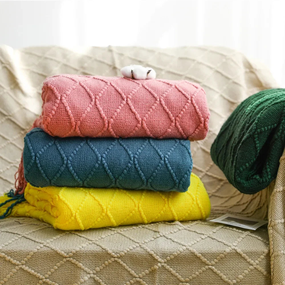 Stack of pink, blue, yellow, and green diamond-textured knit blankets