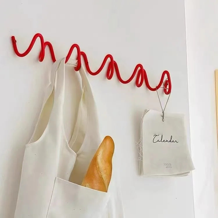 Wave-shaped hook rack with a tote bag and hanging notepad in a modern space