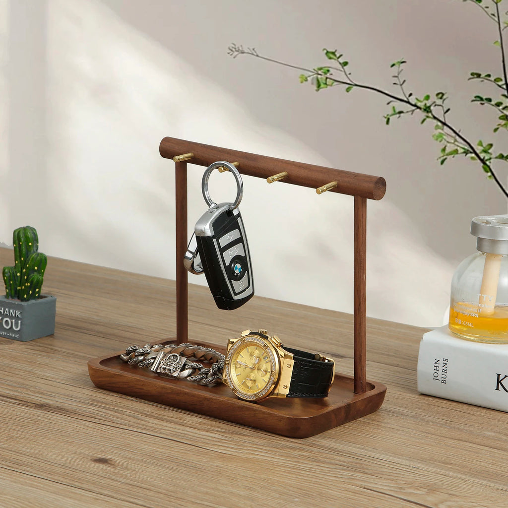 Side view of walnut jewelry organizer holding a key, watch, and bracelet on a wooden tray