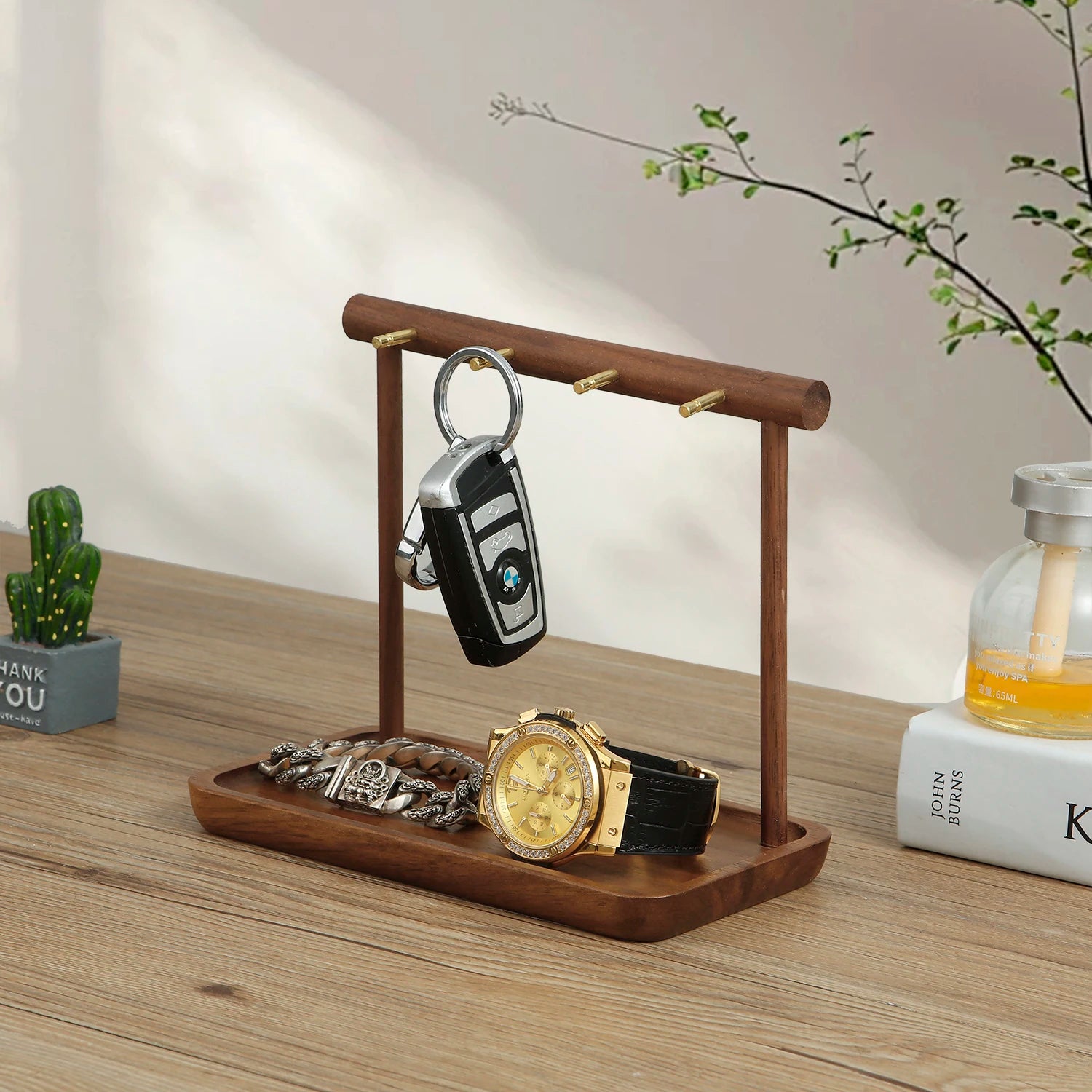 Side view of walnut jewelry organizer holding a key, watch, and bracelet on a wooden tray