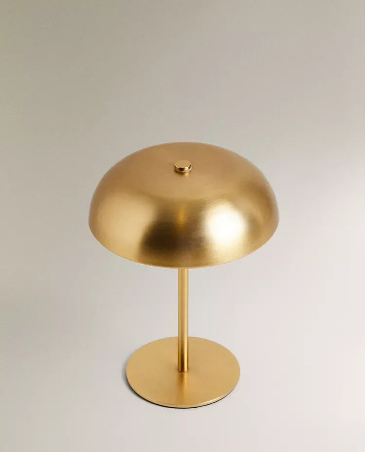 Cordless touch lamp in gold with dome shade on light background