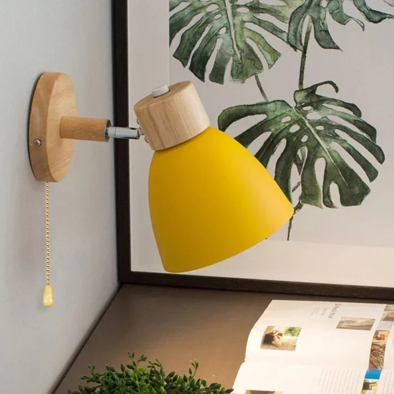 yellow wall-mounted sconce with wood base next to a desk and plant