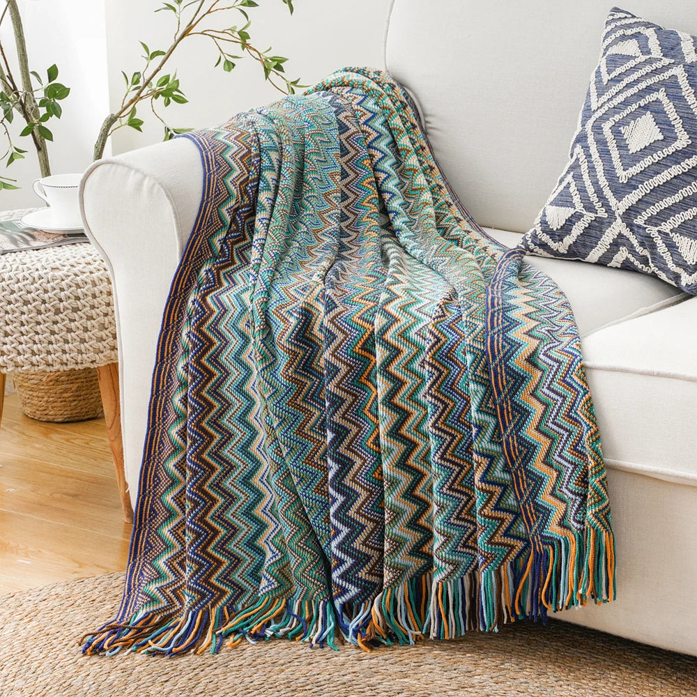 Bohemian zigzag knit throw blanket with tassels draped on a sofa in a bright living room setting