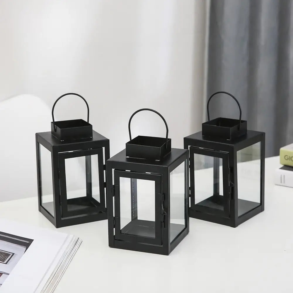 Three empty black iron square lanterns arranged on a white table