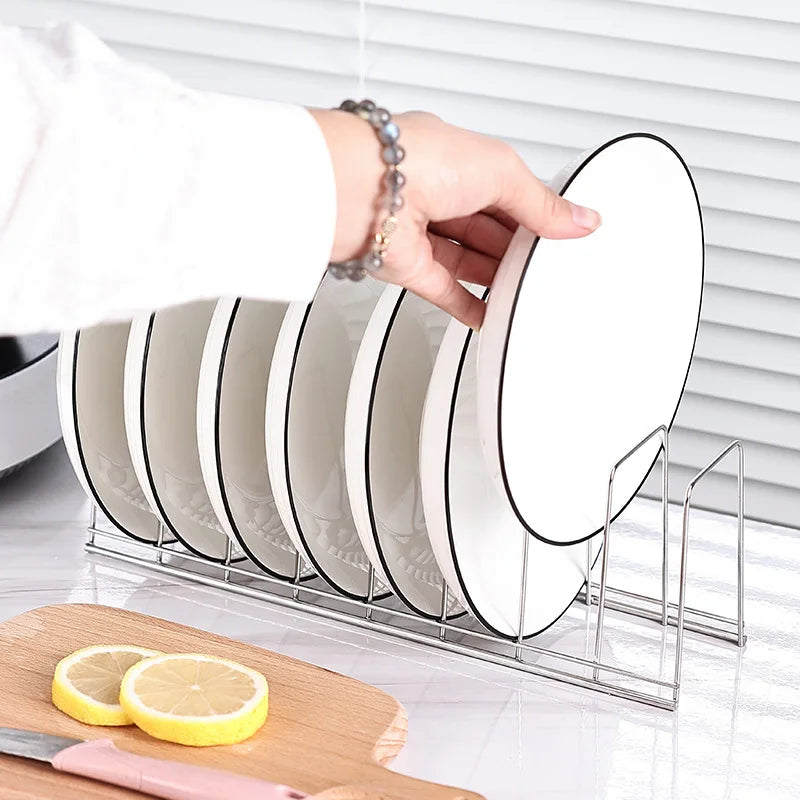 hand placing a white plate with black rim into stainless steel dish rack on kitchen counter