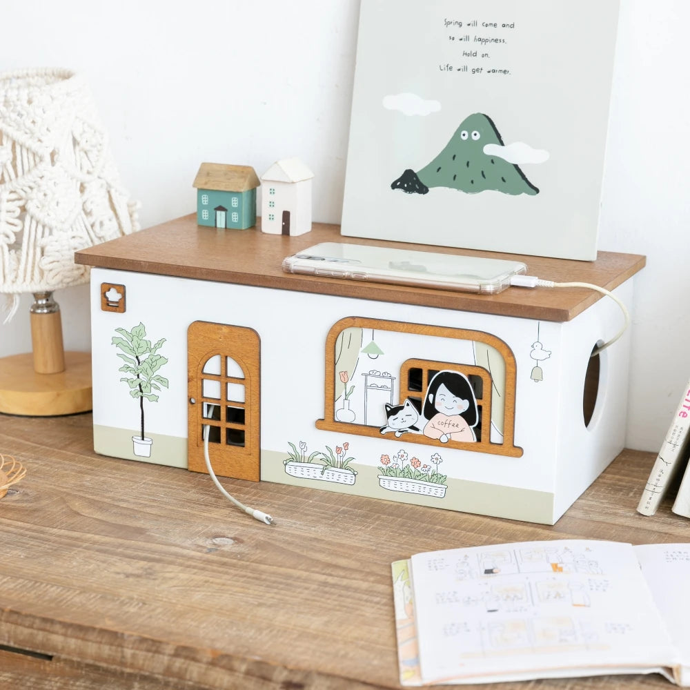 wooden house-shaped cord organizer on sideboard near lamp