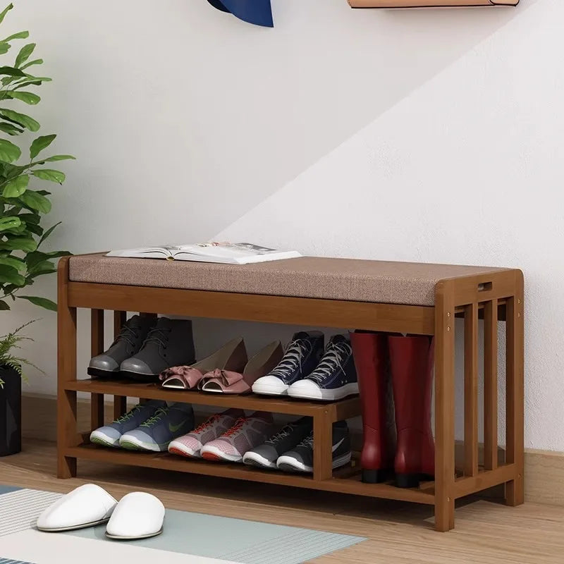 Entryway shoe bench holding shoes and rain boots, placed under coat hooks