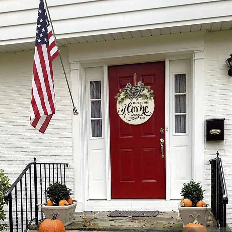 Round welcome sign with bow displayed on a red front door in an outdoor entryway