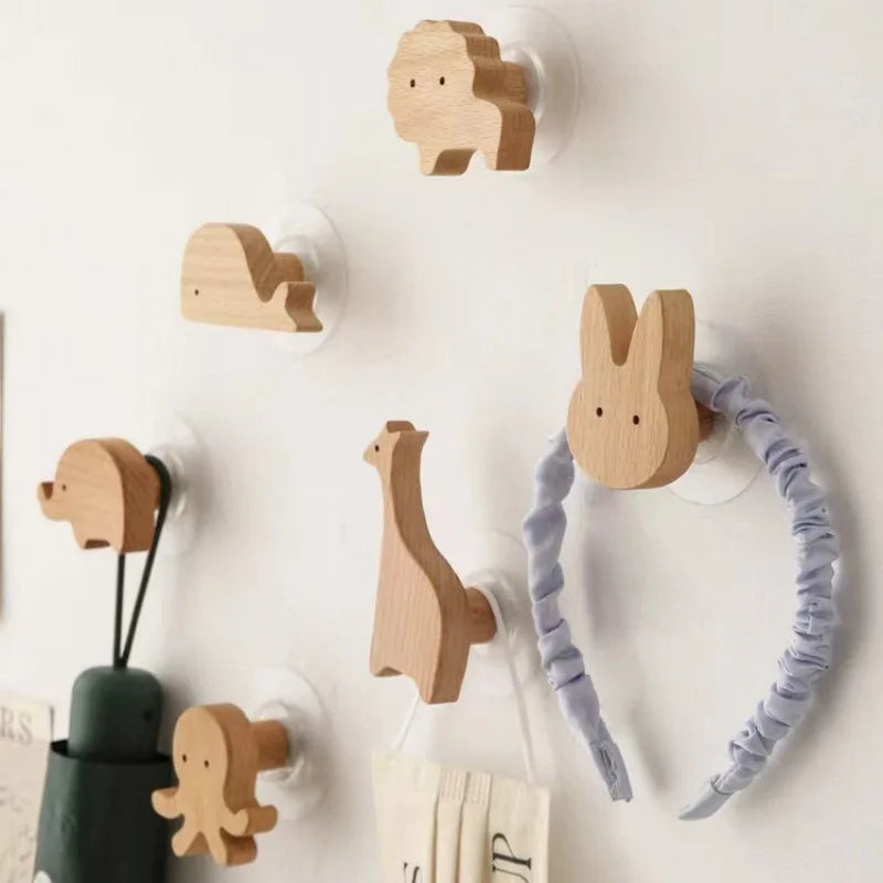 Set of animal shaped wood wall hooks mounted in a child's room, holding bags and accessories