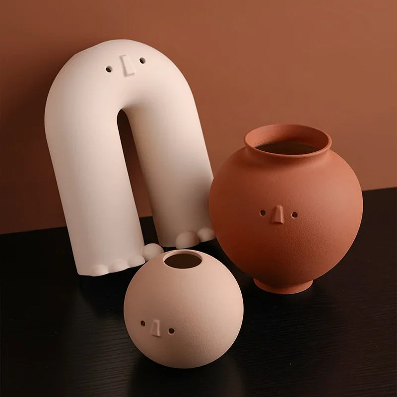 Set of three sculptural face vases in neutral tones, arranged on a dark surface