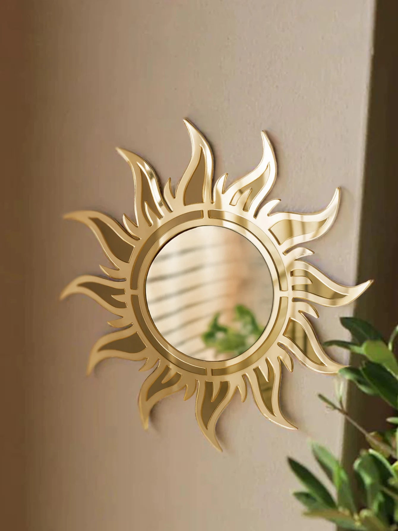 Sun-shaped acrylic wall mirror with reflective center mounted on a light-colored wall