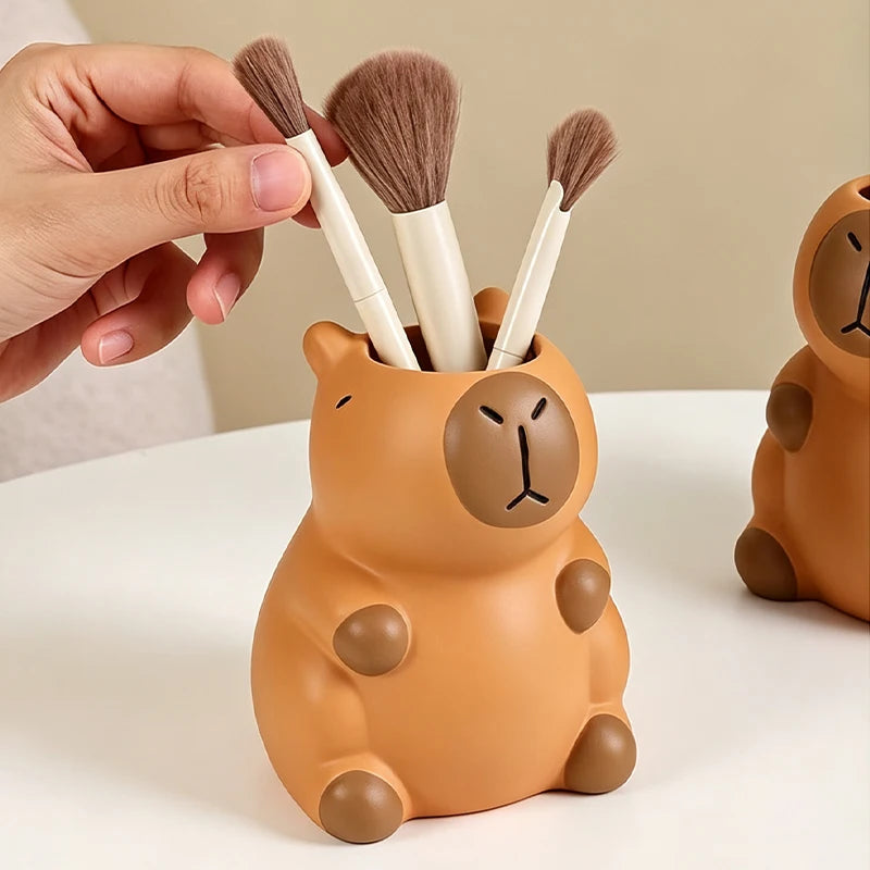 Hand placing a makeup brush in a capybara pen holder on a white table