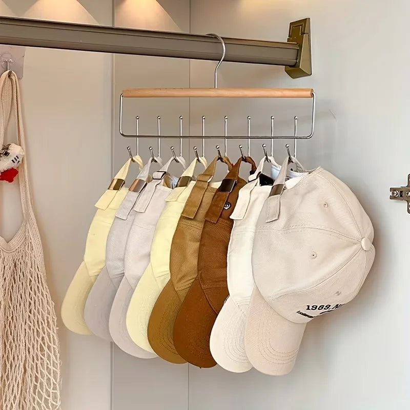 Wooden closet organizer rack hanging from a closet rod with ten baseball caps organized on individual hooks