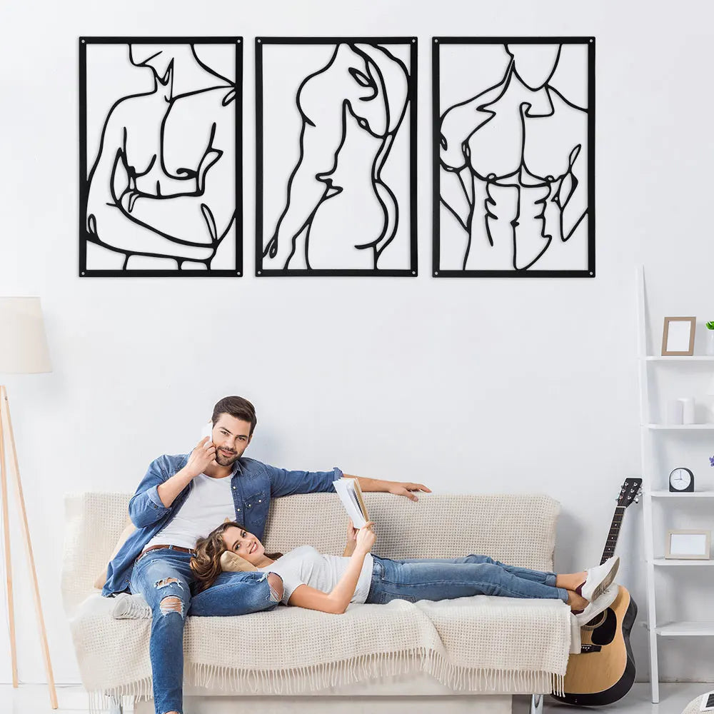 Minimalist black metal line wall art set featuring three abstract body outlines above a sofa with a couple
