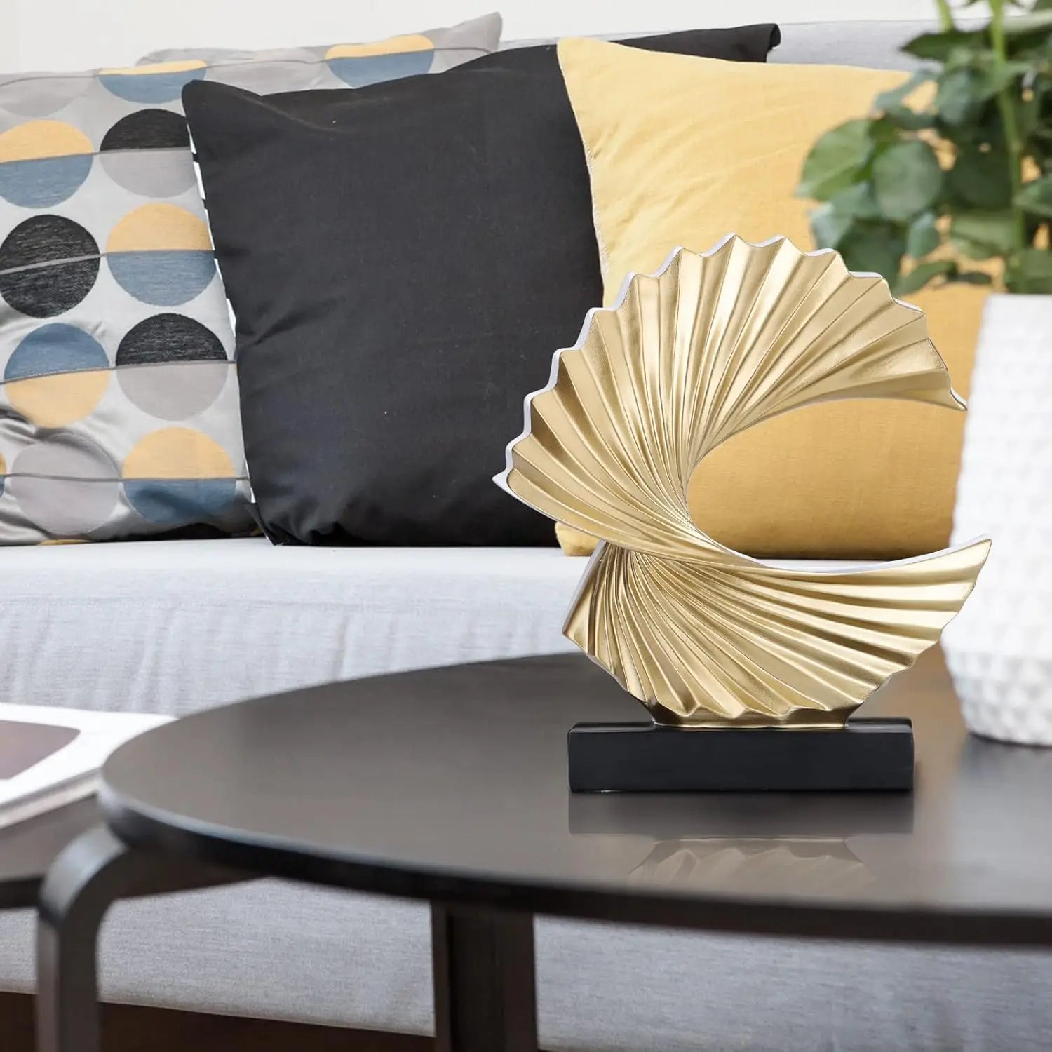 gold abstract wave sculpture on coffee table in living room with patterned pillows